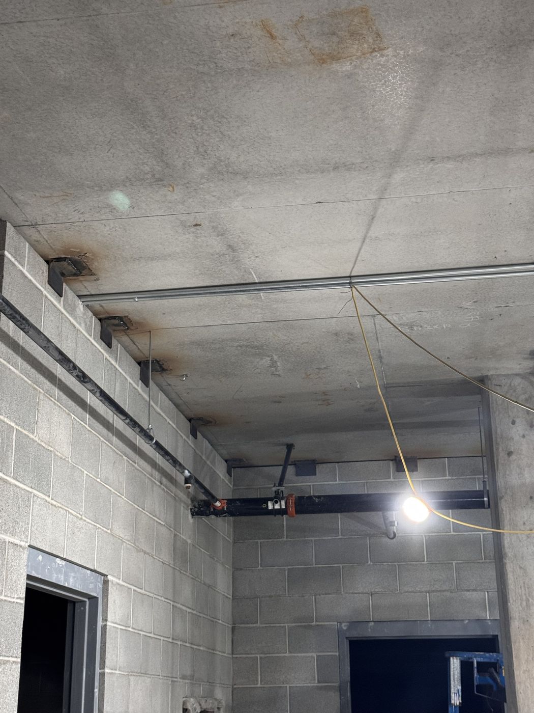 A line of steel clips along the top of a block wall in a corridor, running to the corner