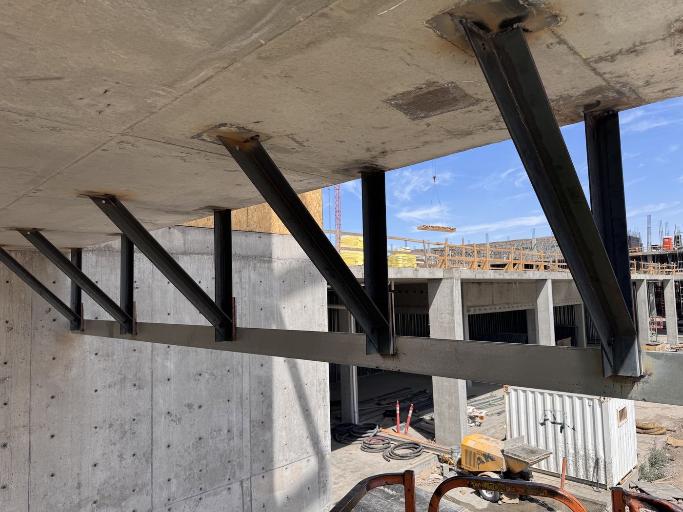 Diagonal steel brackets welded to the underside of a concrete slab, supporting a steel ledger angle
