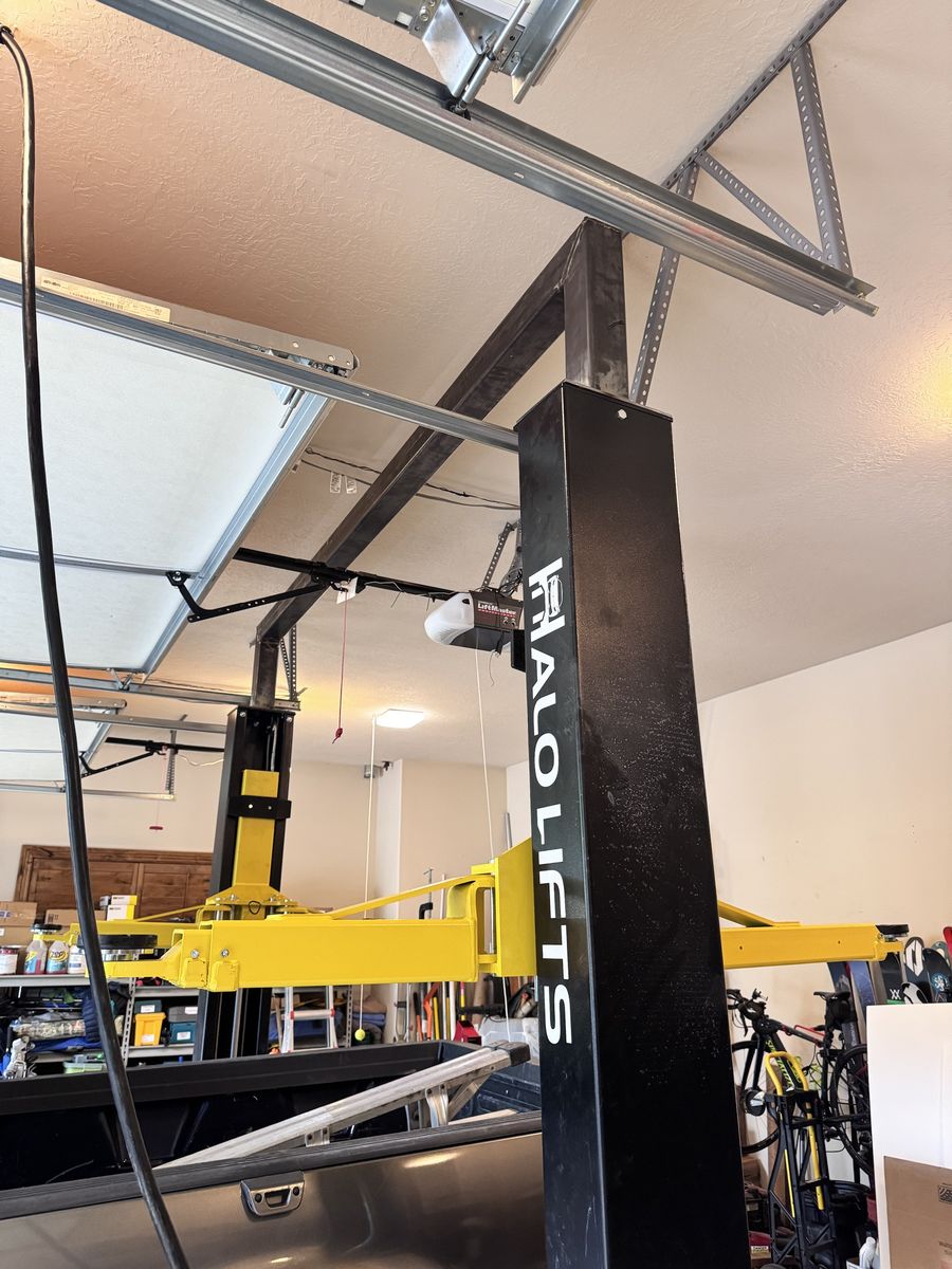 Finished two-post lift column with a welded steel frame running across the garage ceiling