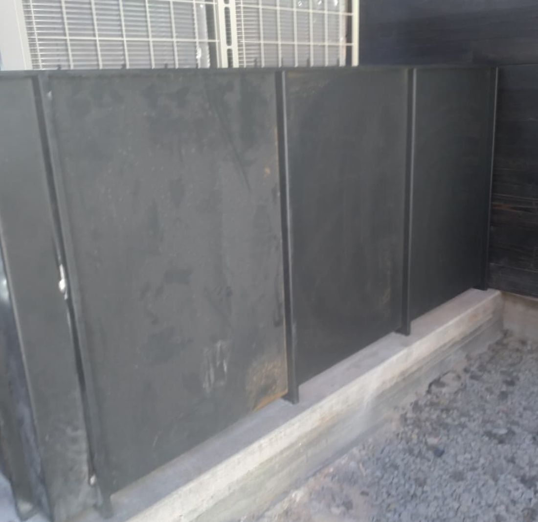 Black steel panels standing in front of outdoor air conditioning units, before the top cap was added