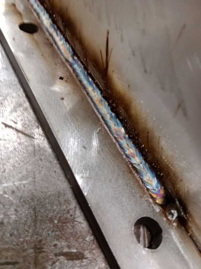 Close-up of a clean weld bead along a flange, with blue and purple heat tint